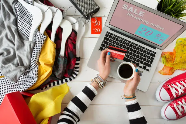 woman holding her cup of coffee while online shopping surrounded by stuff