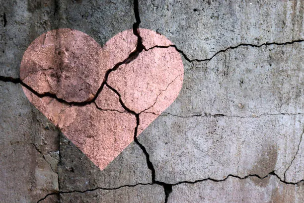 heart painted on a cement wall that is cracking to symbolize unprocessed and invisible grief